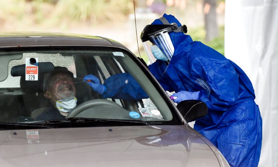 A health worker administers a coronavirus test at a drive-through testing site organized by actor Sean Penn's nonprofit organization Community Organized Relief Effort (CORE) at Malibu City Hall in Malibu, California. (AP Photo/Chris Pizzello)