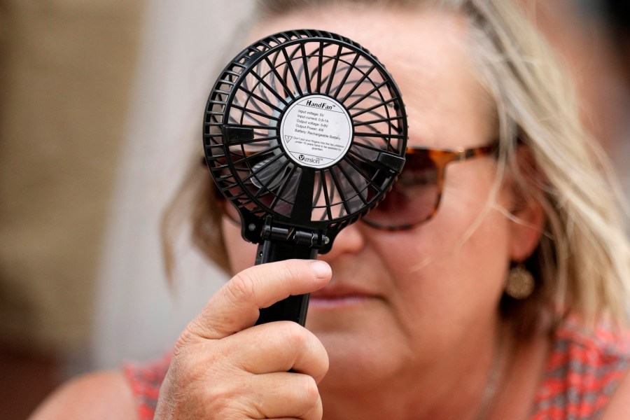 A Houston Astros fan uses a hand fan to keep cool while waiting to enter Minute Maid Park for baseball game against the Cincinnati Reds Saturday, June 17, 2023, in Houston. (AP Photo/David J. Phillip)