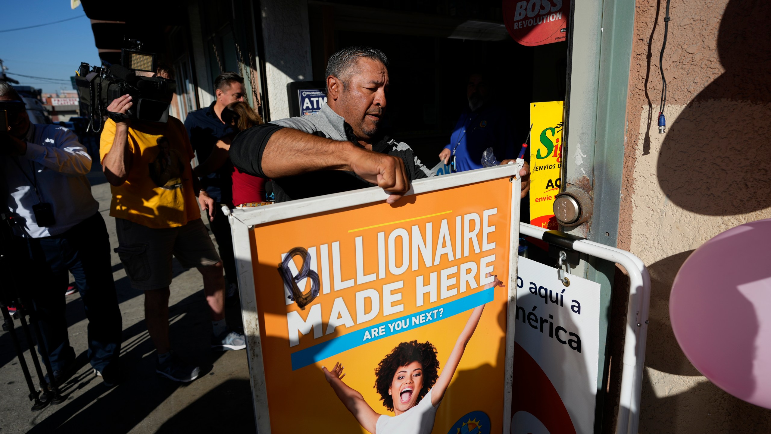 Hector Avalos puts up a sign outside the Las Palmitas Mini Market where the winning Powerball lottery ticket was sold in downtown Los Angeles, Thursday, July 20, 2023. The winning ticket for the Powerball jackpot is worth an estimated $1.08 billion and is the sixth largest in U.S. history and the third largest in the history of the game. (AP Photo/Marcio Jose Sanchez)