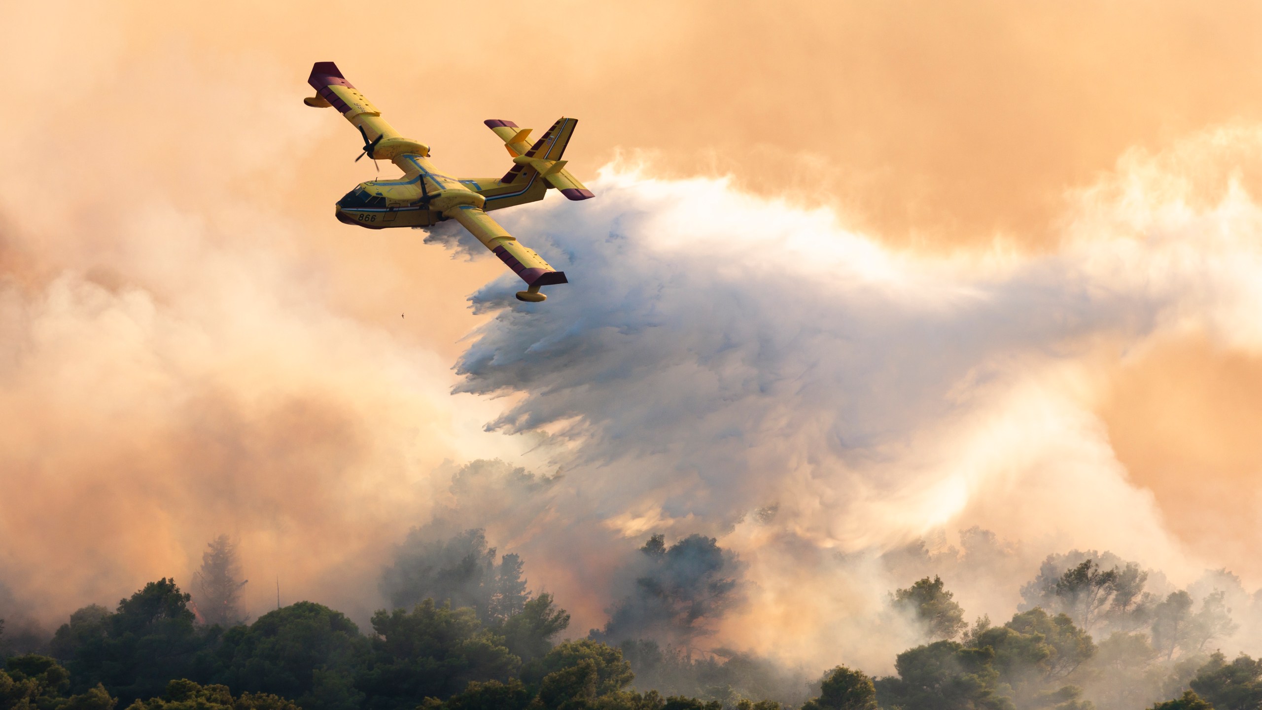 A firefighting plane sprays water to extinguish a wildfire . (AP Photo/Miroslav Lelas)