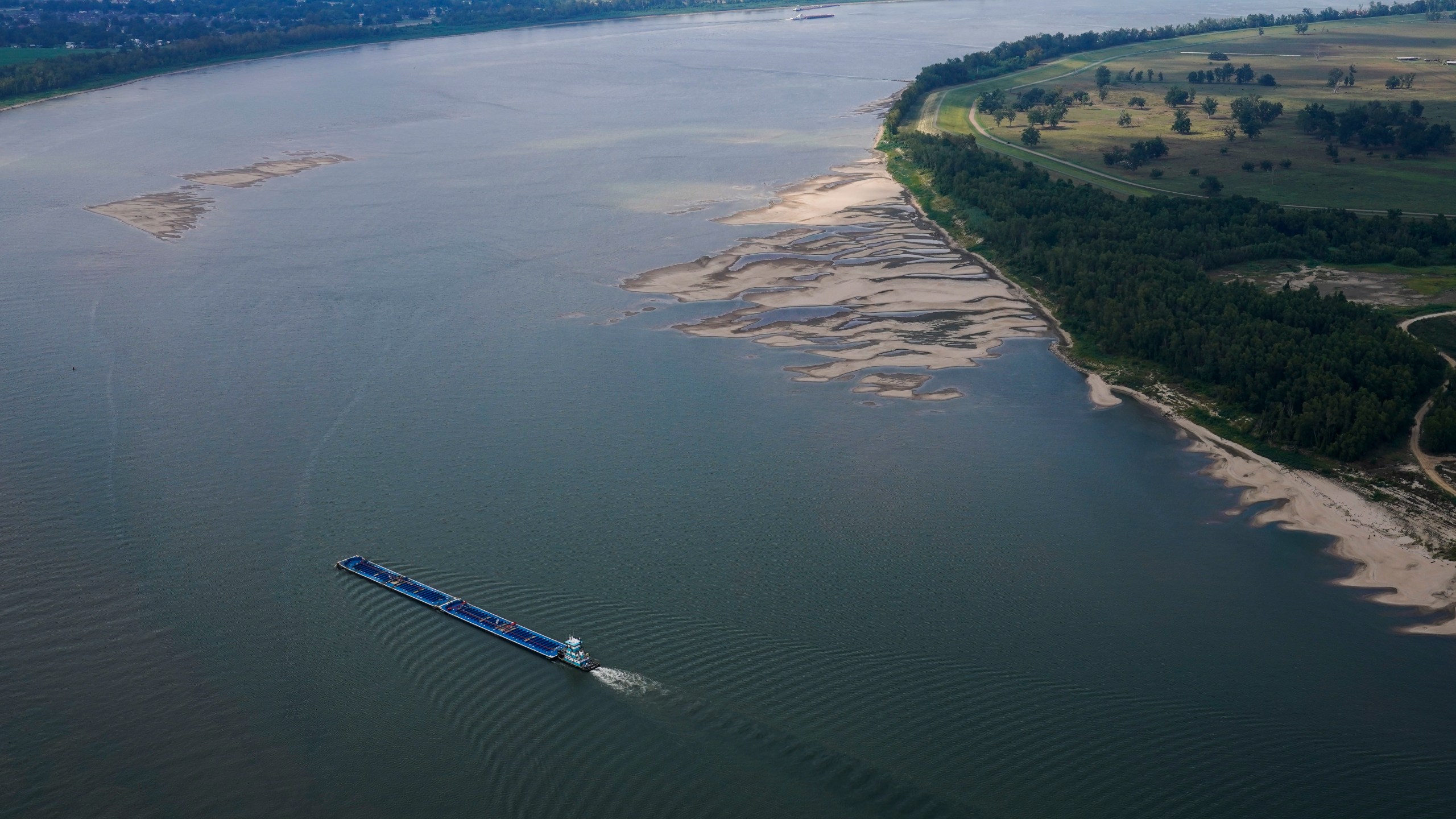 In this aerial photo, a tugboat pushing barges navigates between and around sandbars during low water levels on the Mississippi River between Baton Rouge, La., and Reserve, La., in Livingston Parish, La., Thursday, Sept. 14, 2023. (AP Photo/Gerald Herbert)