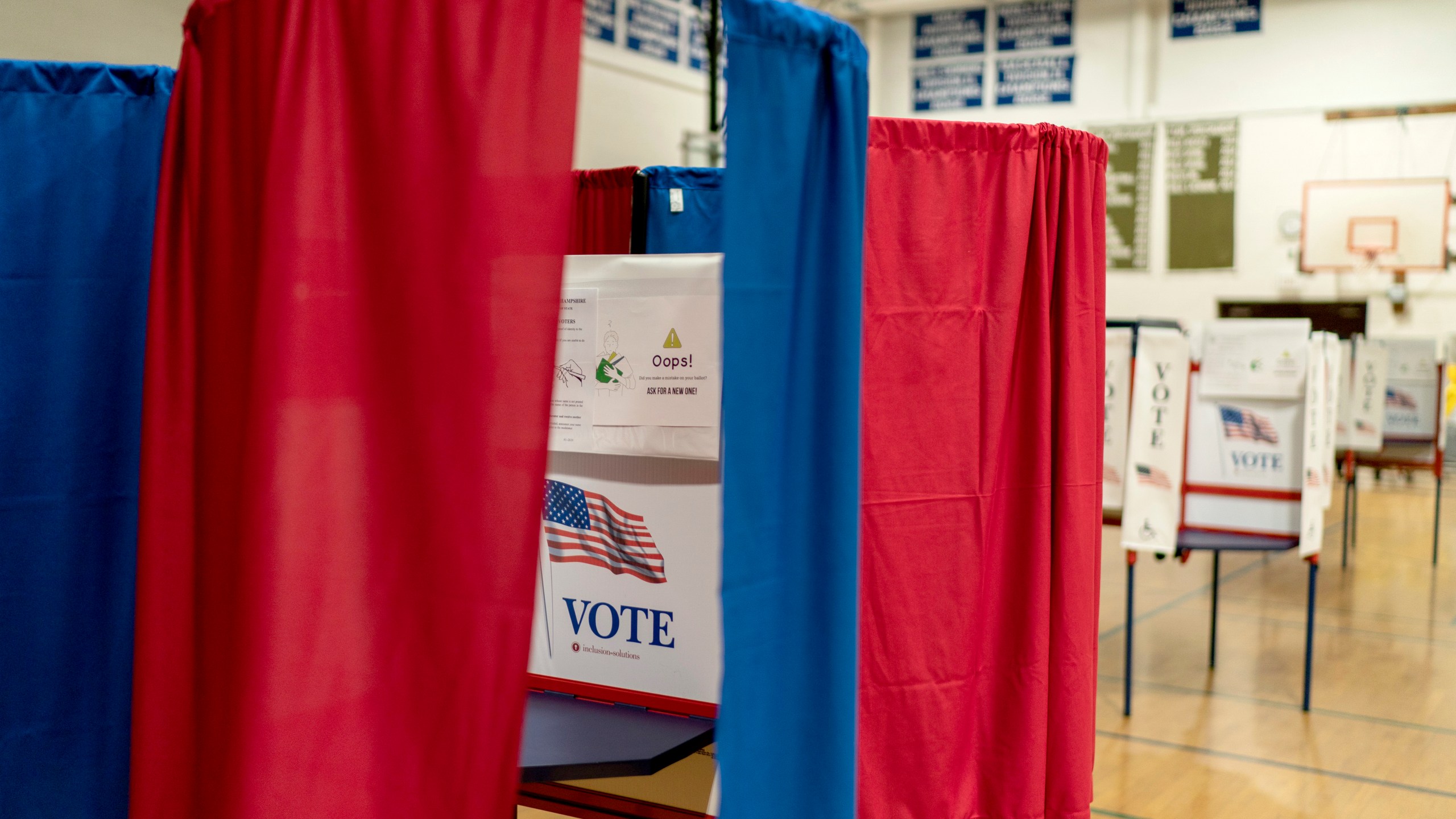 FILE - Voting booths are set up in a high school gymnasium in Hollis, N.H., Jan. 22, 2024. Though you may start to hear President Joe Biden and former president Donald Trump referred to as their parties' "presumptive nominees," the Associated Press only uses that term once a candidate has won the number of delegates needed to win a majority vote at the national party conventions this summer. (AP Photo/David Goldman)