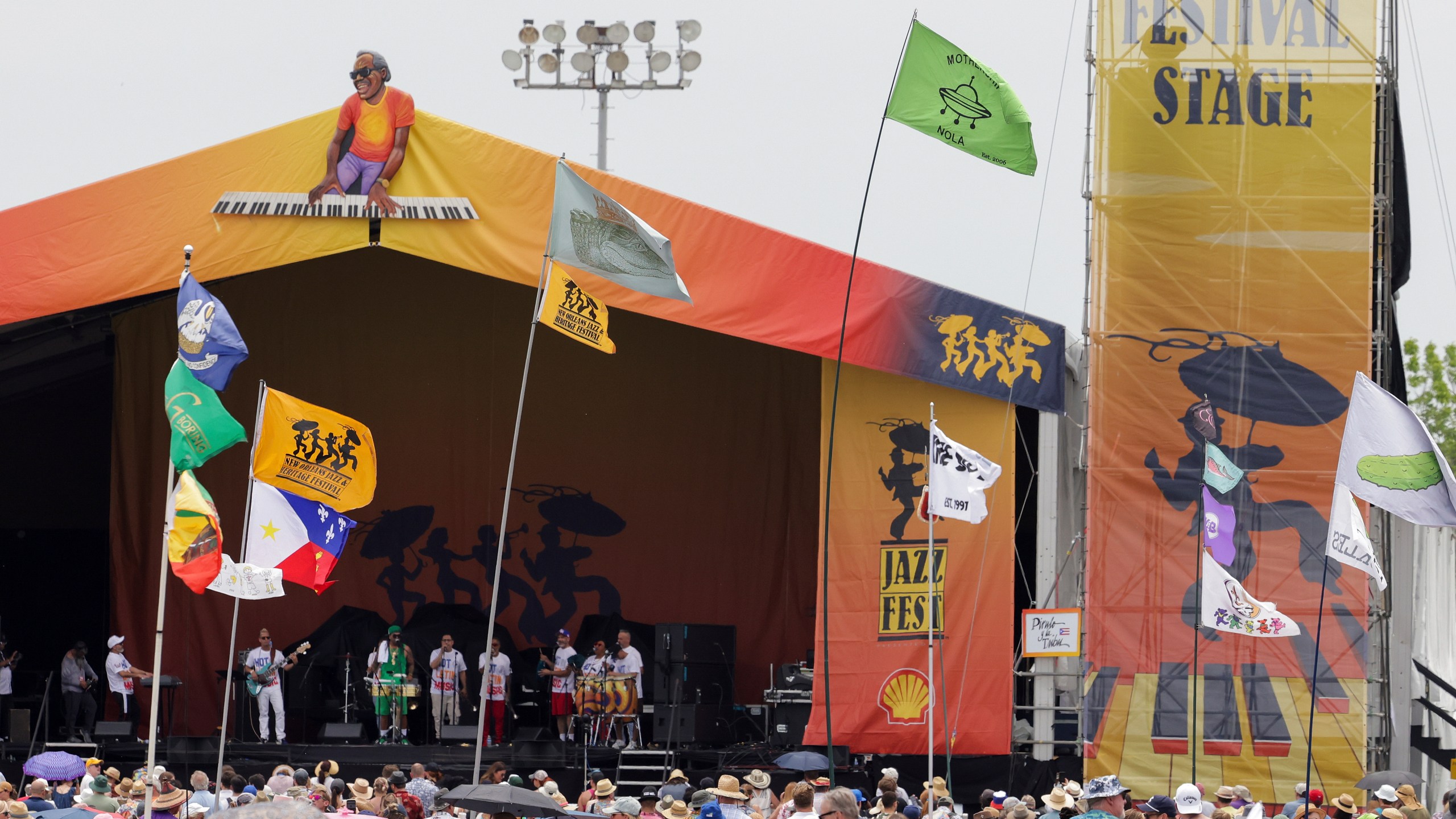 FILE - Flags fly in front of the Festival Stage during the New Orleans Jazz & Heritage Festival on May 7, 2023. The Fair Grounds Race Course, which plays host to the 2024 New Orleans Jazz and Heritage Festival, begins its annual transformation in earnest Tuesday, March 26, 2024, as organizers prepare to take over the field this Spring for two weekends of music, food and fun. (Brett Duke/The Advocate via AP, File)