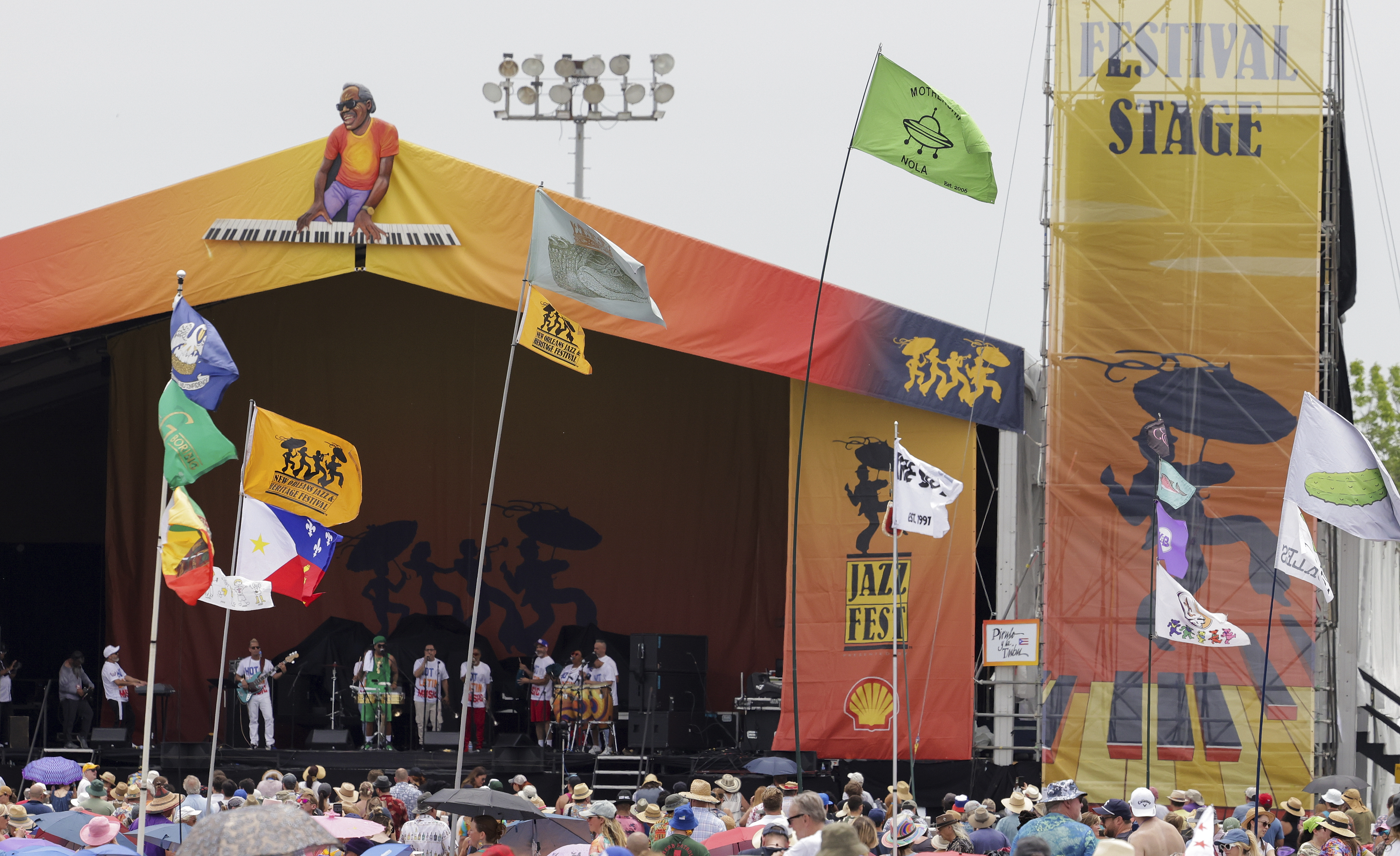 FILE - Flags fly in front of the Festival Stage during the New Orleans Jazz & Heritage Festival on May 7, 2023. The Fair Grounds Race Course, which plays host to the 2024 New Orleans Jazz and Heritage Festival, begins its annual transformation in earnest Tuesday, March 26, 2024, as organizers prepare to take over the field this Spring for two weekends of music, food and fun. (Brett Duke/The Advocate via AP, File)