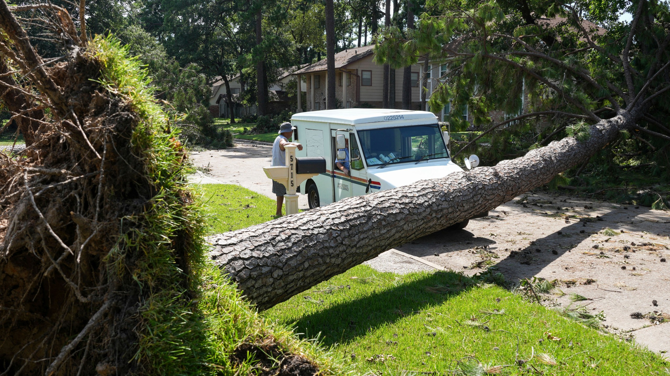 Delray Gooch, standing, talks to mail carrier Jason Phillips as he delivers mail in the aftermath of Hurricane Beryl on Wednesday, July 10, 2024, in Houston. (Jon Shapley/Houston Chronicle via AP)