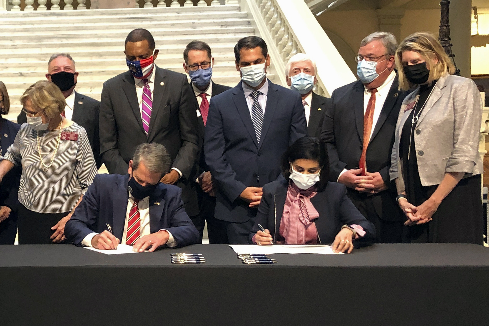 FILE - Georgia Gov. Brian Kemp, left, and Centers for Medicare and Medicaid Services Administrator Seema Verma, right, sign healthcare waivers at the state Capitol in Atlanta, Oct. 15, 2020. Pathways to Coverage launched last July and is the only Medicaid plan in the country that requires beneficiaries to work or engage in other activities to get coverage. As of June, it had about 4,300 members. (AP Photo/Jeff Amy, File)