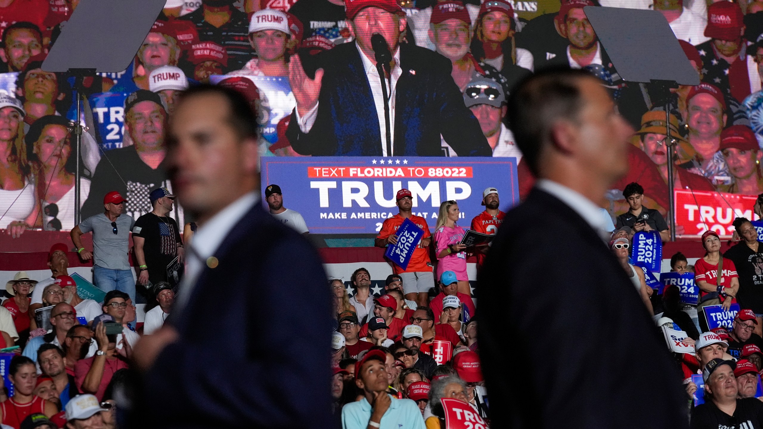 U.S. Secret Service agents watch as an image of Republican presidential candidate former President Donald Trump is shown on a screen at a campaign rally at Trump National Doral Miami, Tuesday, July 9, 2024, in Doral, Fla. (AP Photo/Rebecca Blackwell)