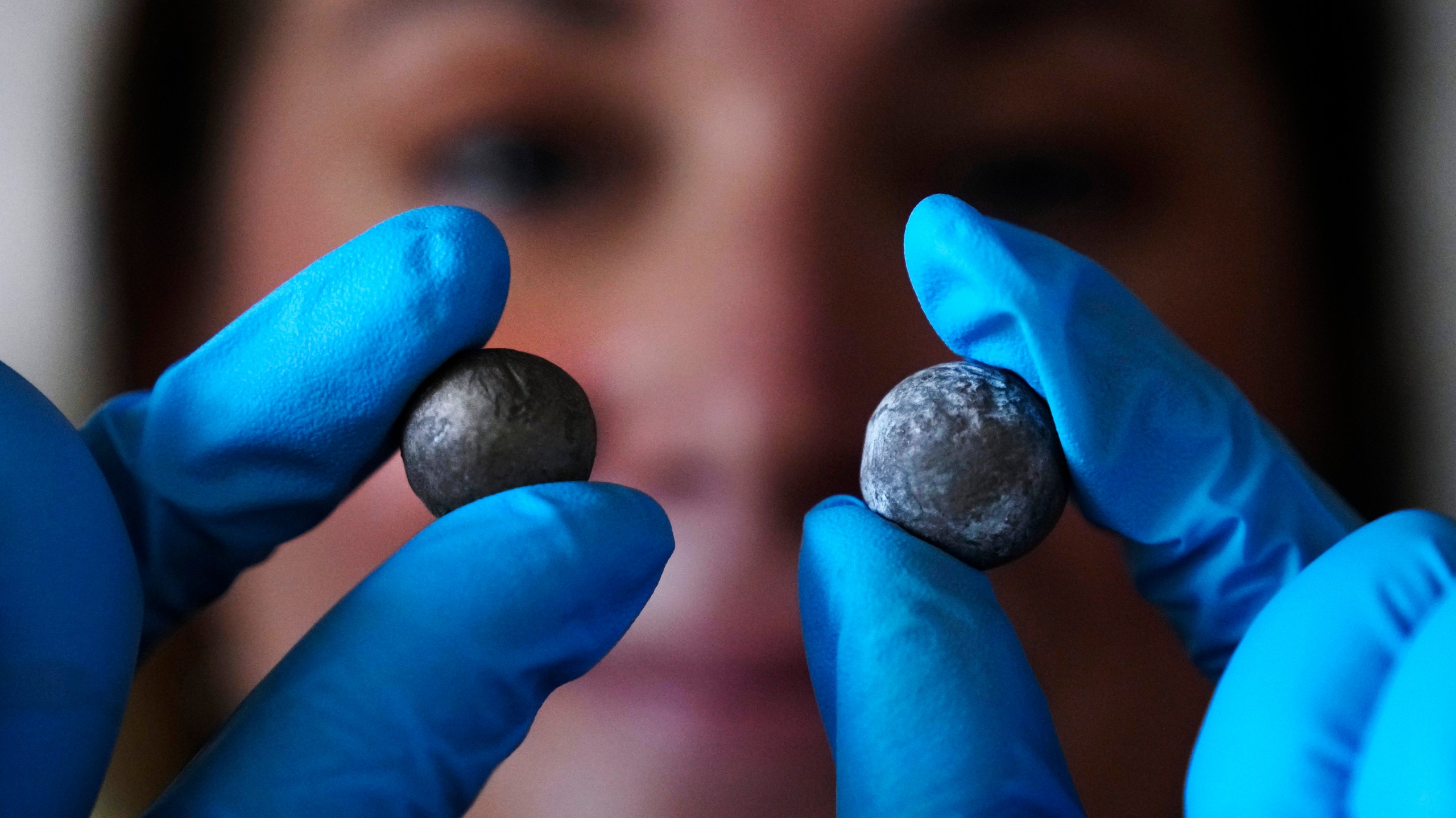 Museum curator Nikki Walsh holds up two Revolutionary War musket balls, which are believed to be fired at the British by colonial militia men, at Minute Man National Historical Park, Monday, July 15, 2024, in Concord, Mass. Archeologists say the musket balls date back nearly 250 years and were fired during one of the first battles in the Revolutionary War. (AP Photo/Charles Krupa)