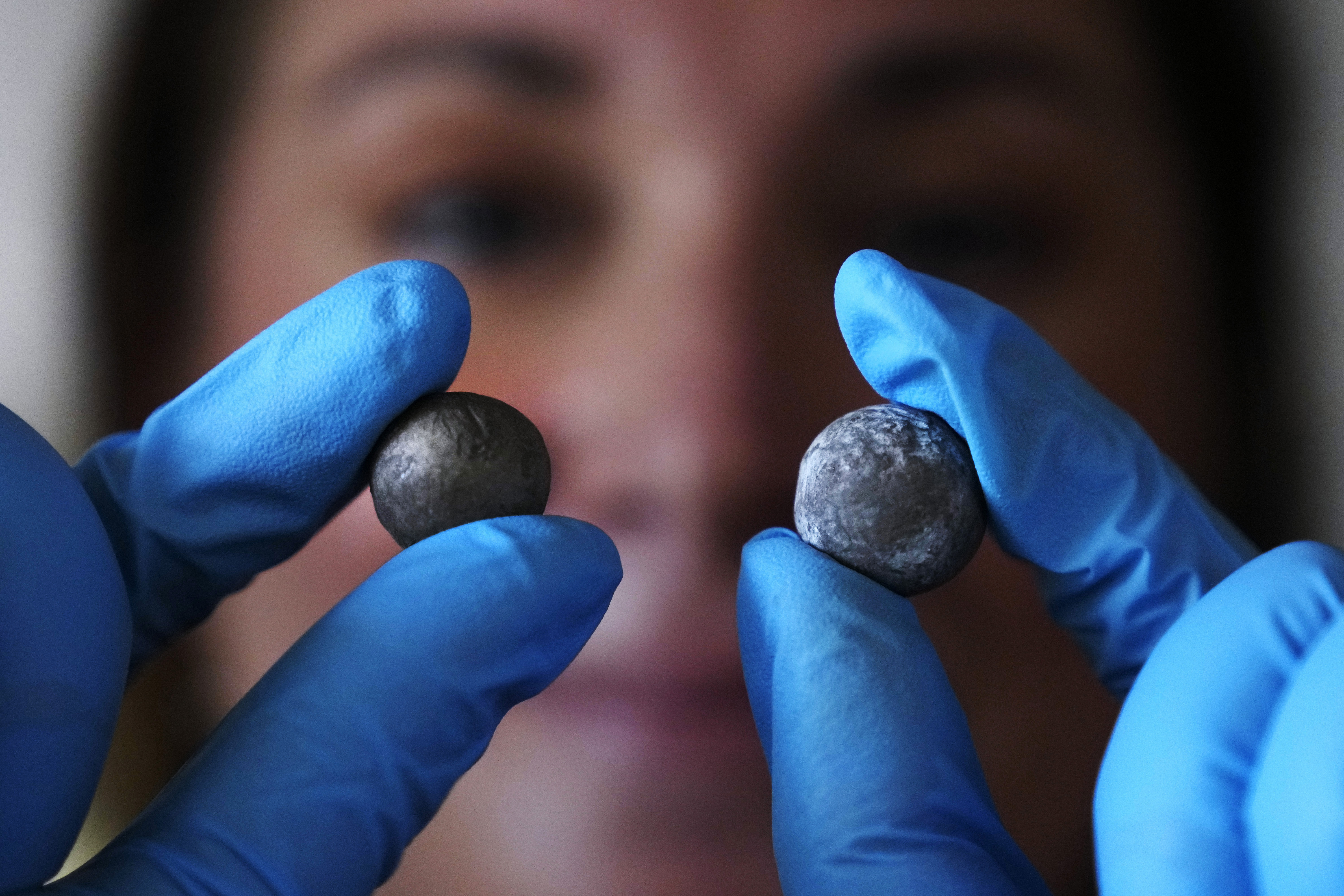 Museum curator Nikki Walsh holds up two Revolutionary War musket balls, which are believed to be fired at the British by colonial militia men, at Minute Man National Historical Park, Monday, July 15, 2024, in Concord, Mass. Archeologists say the musket balls date back nearly 250 years and were fired during one of the first battles in the Revolutionary War. (AP Photo/Charles Krupa)