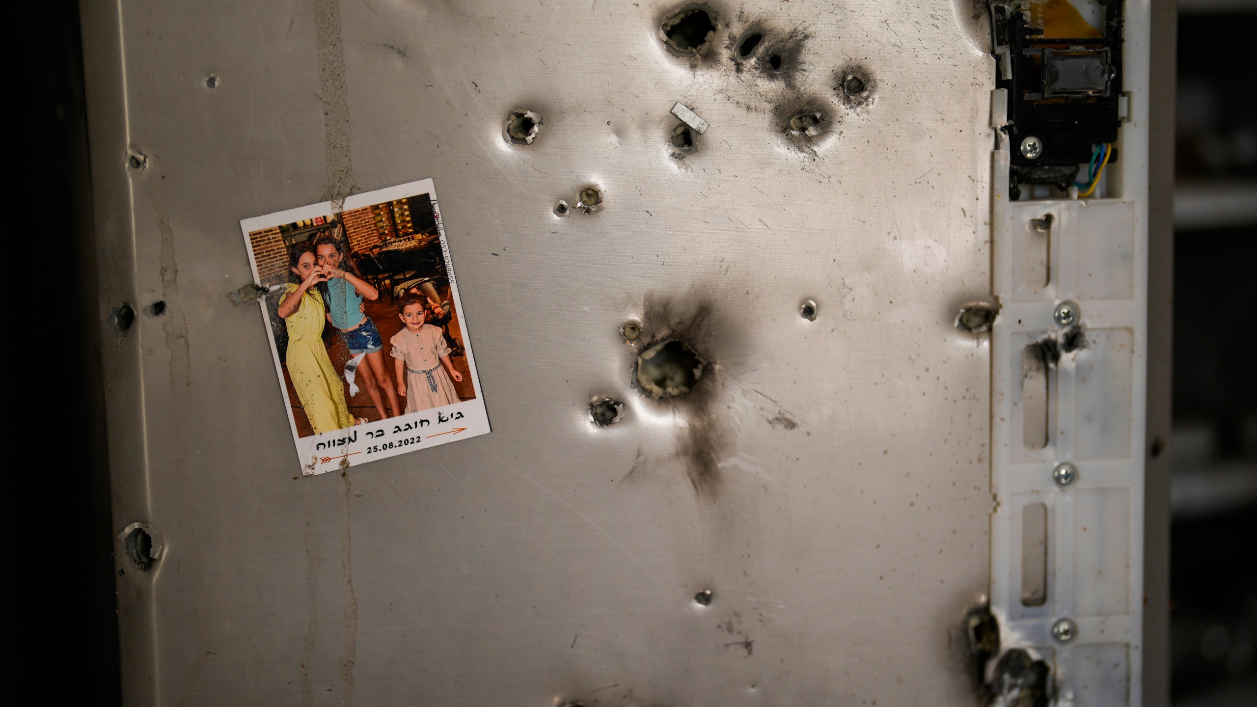 FILE - A photo hangs on a refrigerator next to bullet holes in a house at Kibbutz Kissufim in southern Israel, Saturday, Oct. 21, 2023. The Kibbutz was overrun by Hamas militants from the nearby Gaza Strip on Oct. 7, when they killed and captured many Israelis. Human Rights Watch released a report Wednesday, July 17, 2024, saying Hamas-led armed groups committed numerous war crimes during the Oct. 7 attack on southern Israel that precipitated the ongoing war in the Gaza Strip. (AP Photo/Francisco Seco, File)