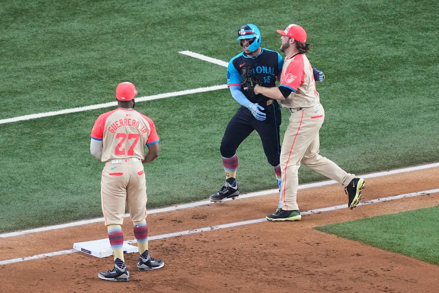 National League's William Contreras, center, of the Milwaukee Brewers, jokes around with American League's Corbin Burnes, right, during the first inning of the MLB All-Star baseball game, Tuesday, July 16, 2024, in Arlington, Texas. (AP Photo/Tony Gutierrez)