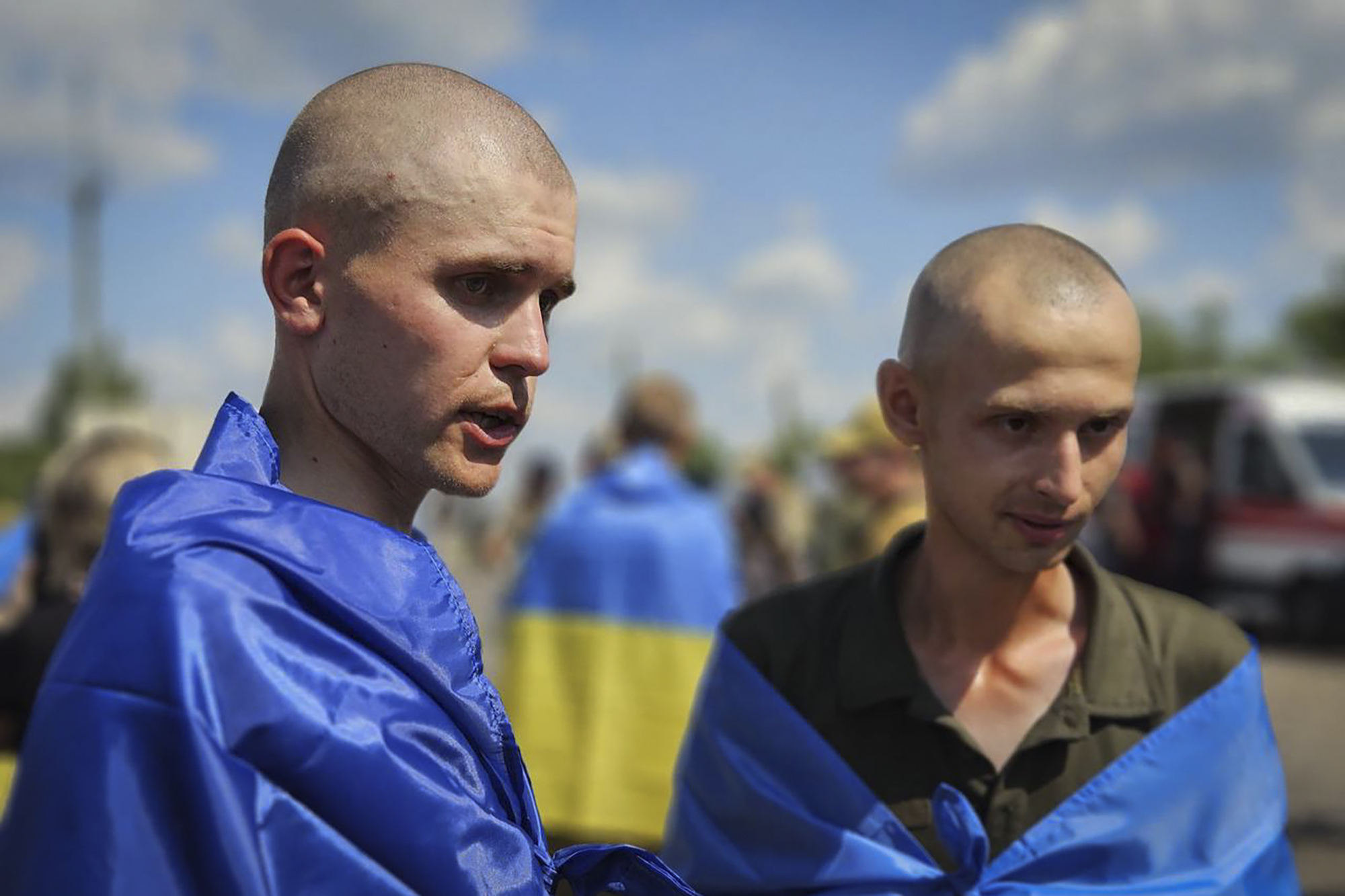 In this photo provided by the Ukrainian Presidential Press Office on Wednesday, July 17, 2024, Ukrainian prisoners of war wrapped in national flags pose for a photo after a prisoners exchange at an undisclosed location in Ukraine. (Ukrainian Presidential Press Office via AP)