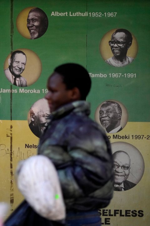 A woman walks past a wallpaper with portraits of the former ruling party presidents outside Luthuli House in downtown Johannesburg, South Africa, Wednesday, July 17, 2024. Former South African President Jacob Zuma was expected to face a disciplinary hearing with the African National Congress party on Wednesday, after campaigning against the organization he once led as head of a new political party in national elections in May. (AP Photo/Themba Hadebe)