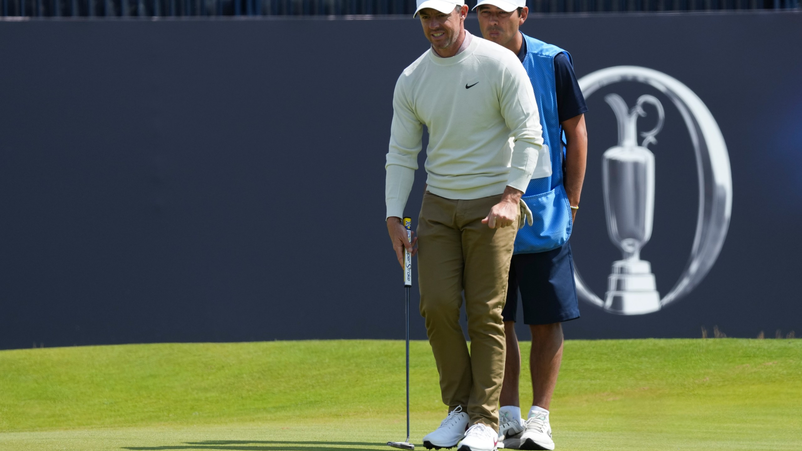 Rory McIlroy of Northern Ireland line sup a putt on the 18th green with his caddy Harry Diamond during a practice round ahead of the British Open Golf Championships at Royal Troon golf club in Troon, Scotland, Wednesday, July 17, 2024. (AP Photo/Jon Super)