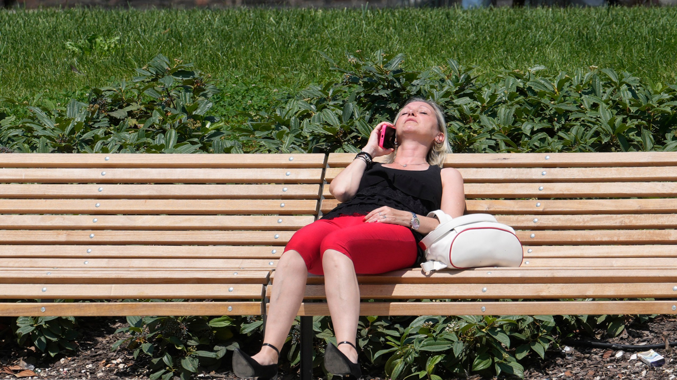 A woman sunbathes in a park in Milan, Italy, Tuesday, July 16, 2024. Weather alerts, forest fires, melting pavement in cities: A sizzling heat wave has sent temperatures in parts of central and southern Europe soaring toward 40 degrees Celsius (104 Fahrenheit) in some places. (AP Photo/Luca Bruno)