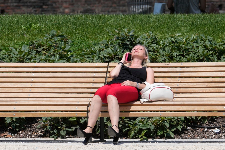 A woman sunbathes in a park in Milan, Italy, Tuesday, July 16, 2024. Weather alerts, forest fires, melting pavement in cities: A sizzling heat wave has sent temperatures in parts of central and southern Europe soaring toward 40 degrees Celsius (104 Fahrenheit) in some places. (AP Photo/Luca Bruno)