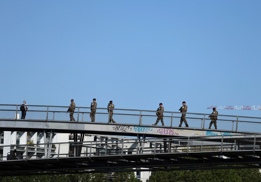 Soldiers patrol on a footbridge over the Seine river, Wednesday, July 17, 2024 in Paris. France's armed forces held a demonstration of the security measures planned on the River Seine, both in and out of the water, to make it safe for athletes and spectators during the opening ceremony of the Paris Olympics. Organizers have planned a parade of about 10,000 athletes through the heart of the French capital on boats on the Seine along a 6-kilometer (3.7-mile) route at sunset on July 26. (AP Photo/Aurelien Morissard)