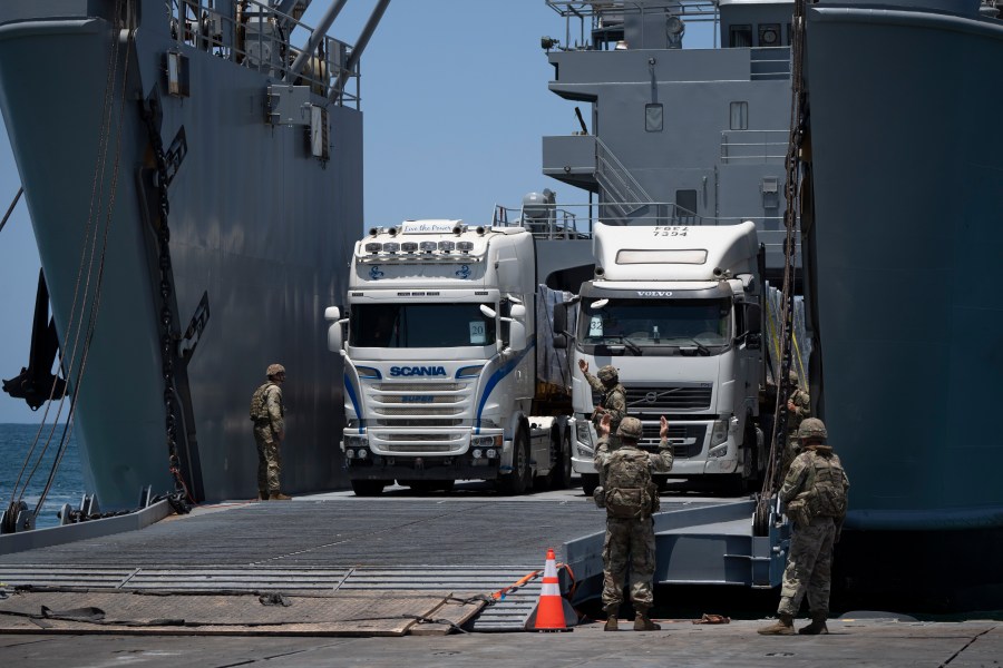 U.S. Army soldiers gestures as trucks loaded with humanitarian aid arrive at the U.S.-built floating pier Trident before reaching the beach on the coast of the Gaza Strip, Tuesday, June 25, 2024. (AP Photo/Leo Correa)